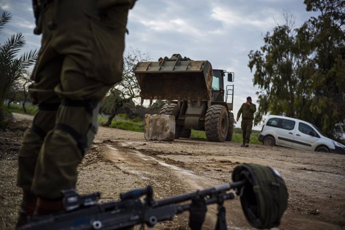 Archivo - 26 March 2019, Israel, Nahal Oz: An Israeli soldier stands next to his machine gun as a bulldozer deploys near the Israel-Gaza border after a long night of rocket attacks and bombing on both sides. Photo: Ilia Yefimovich/dpa