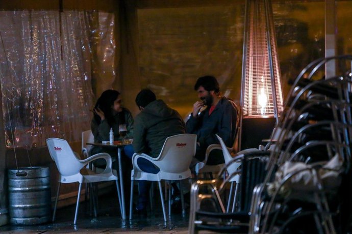 Archivo - Tres jóvenes sentados en la terraza de un bar en Madrid en una imagen de archivo