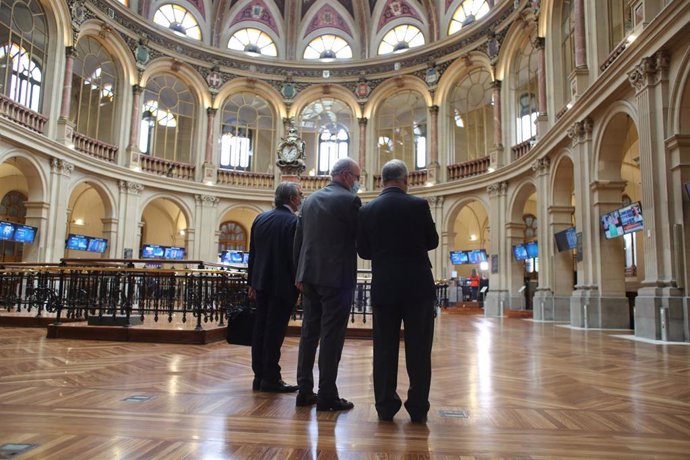 Tres hombres observan valores económicos en el Palacio de la Bolsa
