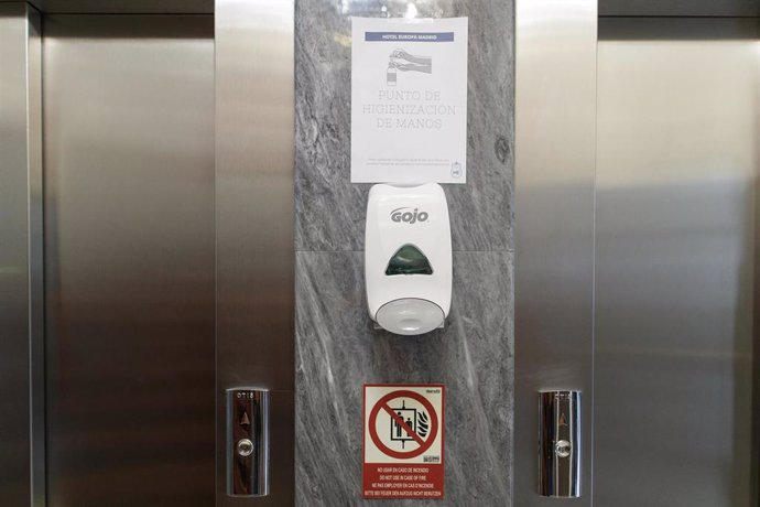 Archivo - Puerta de un ascensor con un cártel que invita a lavarse las manos y un dispensador de jabón 