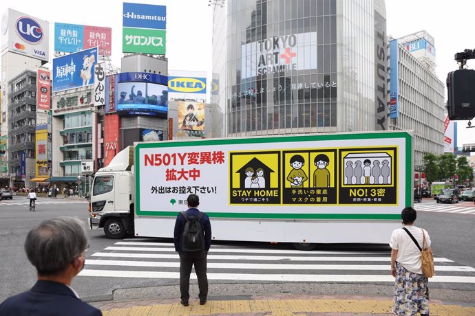 24 May 2021, Japan, Tokyo: A truck with the note "N501Y Coronavirus variation is spreading, please refrain from going outside!" drives around Shibuya Station in Tokyo. Four of these trucks organized by the Tokyo City Government to inform the public on t
