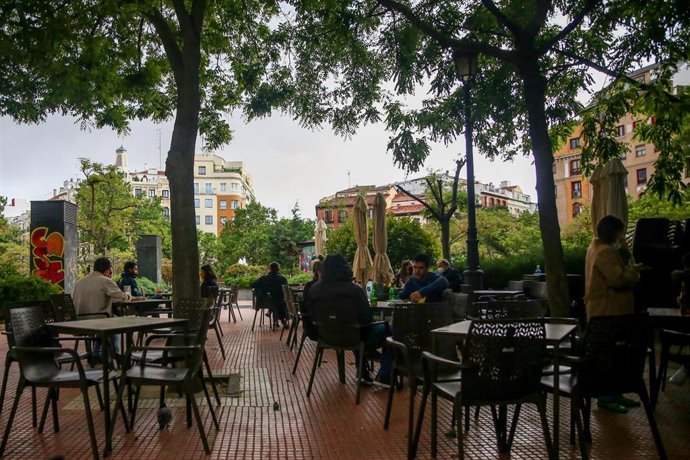Varias personas en la terraza de una cafetería en la plaza de Olavide 