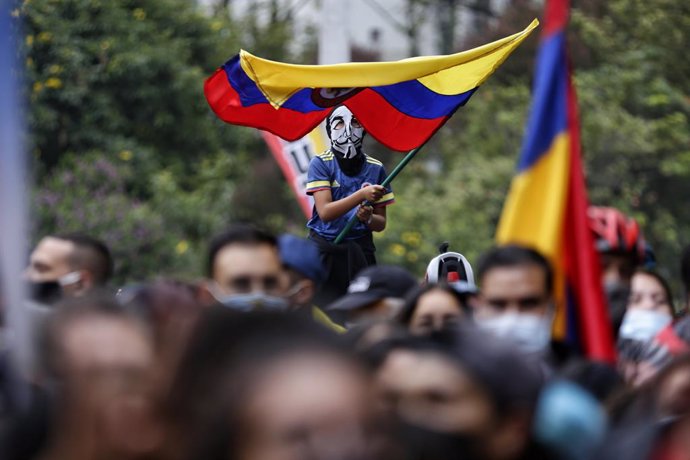 28 May 2021, Colombia, Bogota: A masked child waves a Colombian flag during a protest against the government of President Ivan Duque Marquez. Photo: Sergio Acero/colprensa/dpa