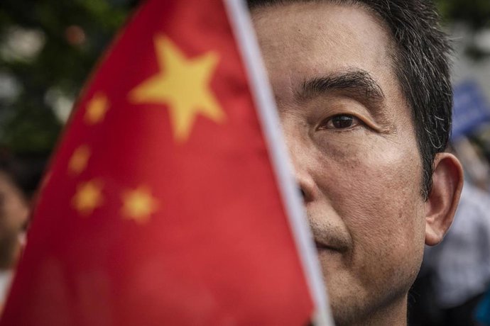 Archivo - Un hombre tras una bandera china en Hong Kong