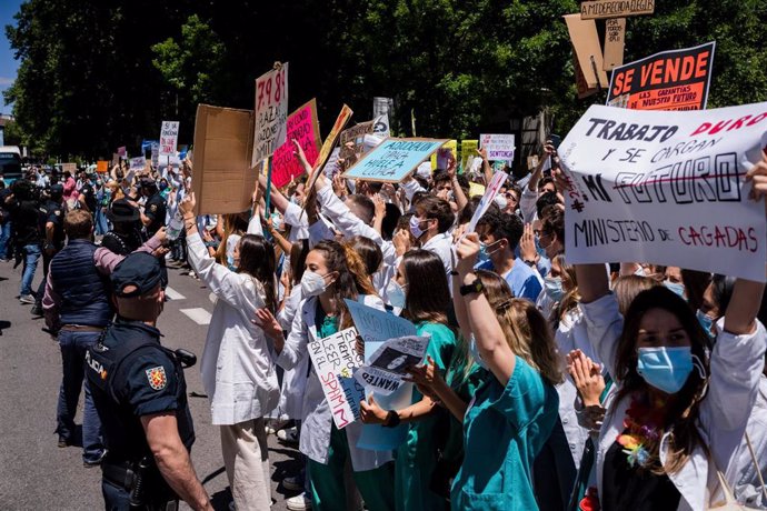 25 May 2021, Spain, Madrid: Police trying to push back protesters during the Resident Internal Doctors (MIR) demonstration in front of the Spanish Ministry of Health, to show their rejection of the new requirements for the choice of specialized health t