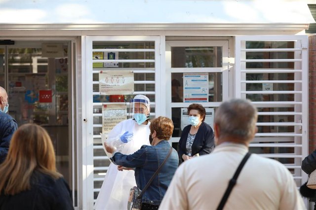 Archivo - Una sanitaria sale a atender a las numerosas personas que hacen cola en el Centro de Salud Vicálvaro-Artilleros en el distrito de Vicálvaro
