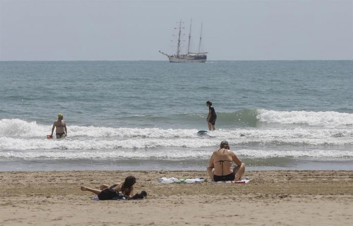 Varias personas se bañan y toman el sol en una playa de Valncia, a 26 de mayo