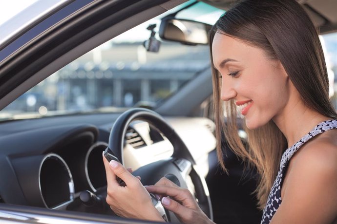 Archivo - Mujer utilizando smartphone en el coche