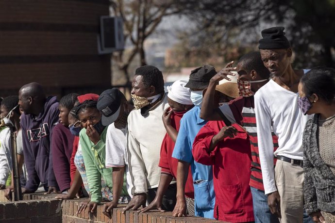 Archivo - Gente con mascarilla en una cola para el reparto de comida en Johannesburgo, Sudáfrica
