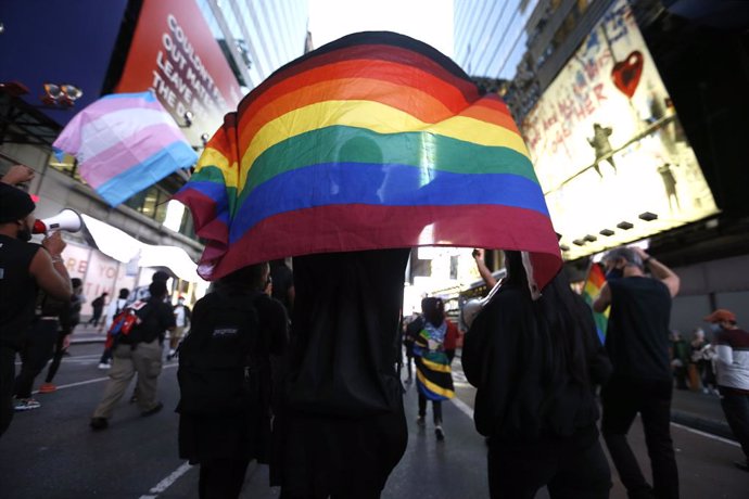 Archivo - 02 October 2020, US, New York: A protestor raises a rainbow flag to show solidarity for the lives of transgender people during a protest in Times Square against the shooting of Roxanne Moore, a transgender woman who was shot 16 times after bra