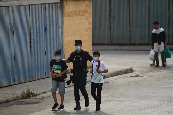 Agentes de la Policía Nacional acompañan a menores marroquíes a las naves acondicionadas anexas a la frontera del Tarajal en Ceuta a 20 de mayo de 2021. 