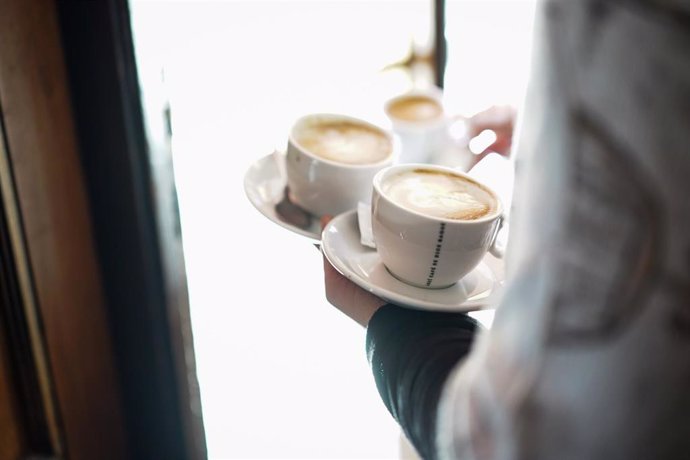 Archivo - Un camarero sirve varios cafés en una cafetería de Vitoria. El sector servicios saca a más de 93.000 personas de las listas del paro.