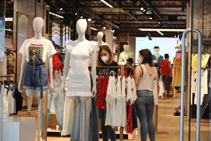Archivo - Personas con mascarilla en el interior de una tienda de ropa 