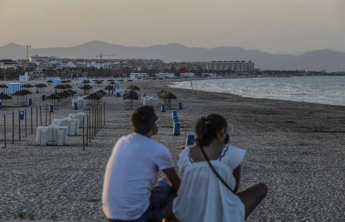 Archivo - Dos jóvenes sentados contemplan la playa de la Malvarrosa durante la noche de San Juan en Valencia, Comunidad Valenciana  (España), a 23 de junio de 2020. Unos 200 agentes de Policía en Valencia blindan las playas de la ciudad en San Juan para