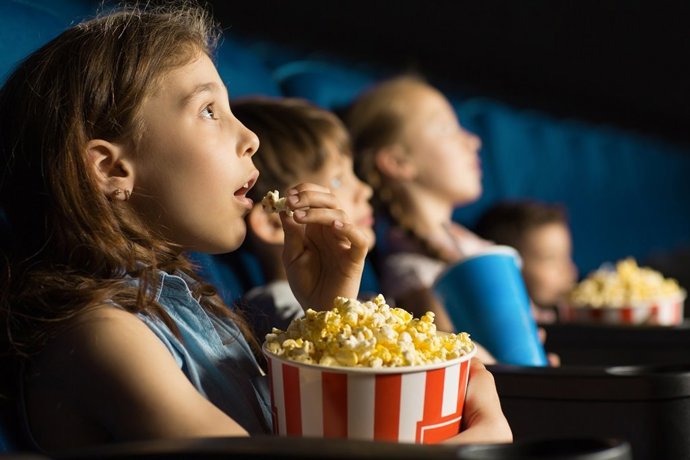 Archivo - Niños comiendo palomitas en el cine