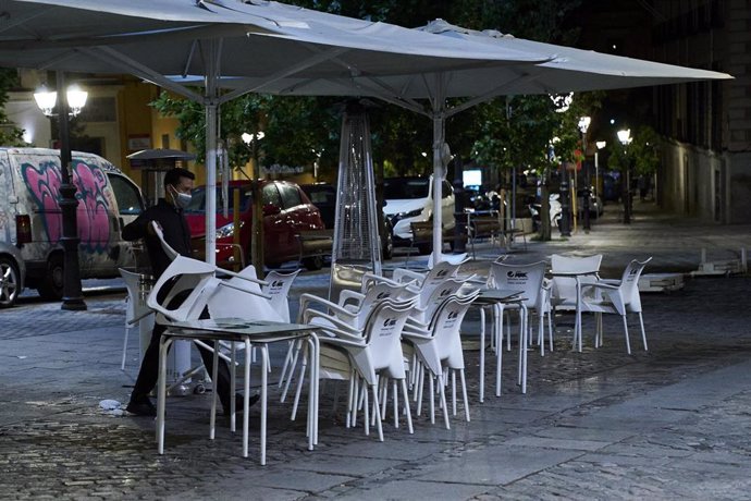 Una persona recoge la terraza de una cafetería en Madrid durante la primera jornada en la que se permite el cierre a la 01.00 en hostelería y recintos culturales, a 31 de mayo de 2021, en Madrid (España). La ampliación de horarios hasta la 01.00 horas e