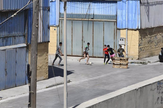 Varios menores acogidos en las naves del Tarajal juega al fútbol.