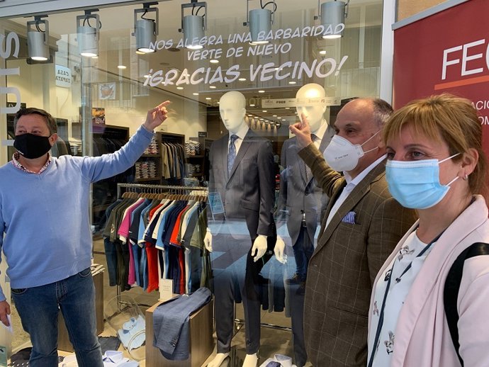 De izda a dcha, Adolfo Sainz, José Luis Jiménez y Yolanda Santos muestran un mensaje de agradecimiento del comercio.