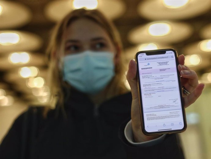 Una mujer de nacionalidad francesa enseña el negativo de su PCR  en un aeropuerto.