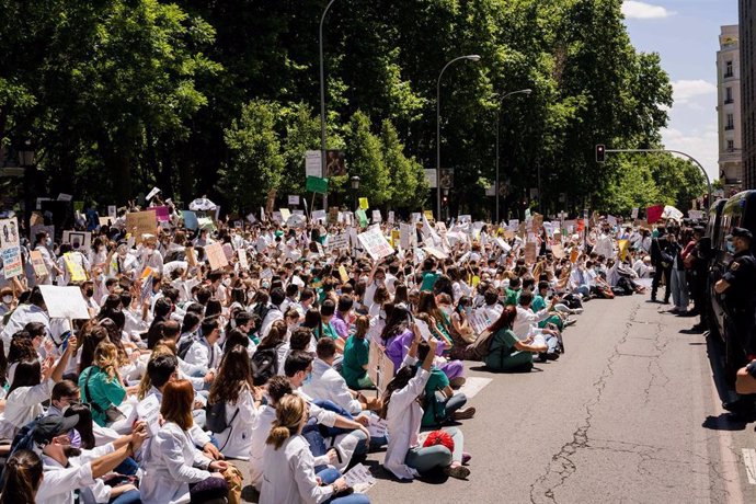 25 May 2021, Spain, Madrid: Protesters sit on the ground blocking the street during the Resident Internal Doctors (MIR) demonstration in front of the Spanish Ministry of Health.