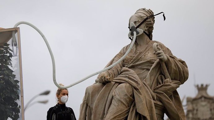 Activistas de Greenpeace colocan una mascarilla a la Cibeles