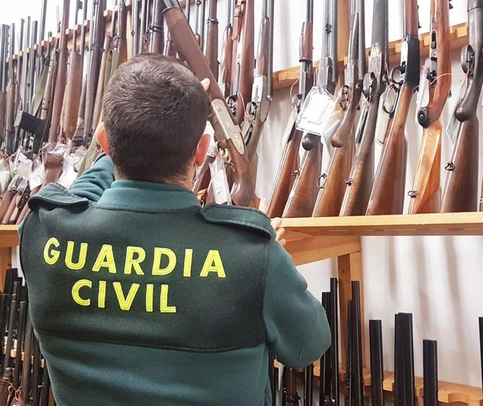 Archivo - Un agente de la Guardia Civil junto a armas para subasta.