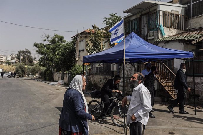 10 May 2021, Israel, Jerusalem: People speak together in front of a tent with the Israeli flag at Jerusalem's Sheikh Jarrah neighbourhood. Some Palestinian families in Sheikh Jarrah are facing eviction from their homes by Israeli authorities, further he