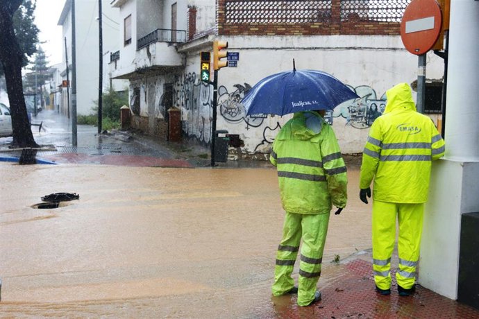 Archivo - Operarios de los servicios operativos ayudan a retirar el exceso de agua acumulada en la barriada de Campanillas tras el desbordamiento del río  a causa de las fuertes lluvias caída la pasada madrugada. Málaga a 31 de marzo del 2020