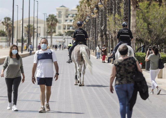 Dos policías municipales patrullan a caballo por un paseo marítimo frente a una playa de Valncia (archivo). 