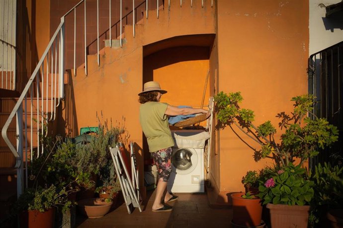 Una mujer ante una lavadora en una terraza