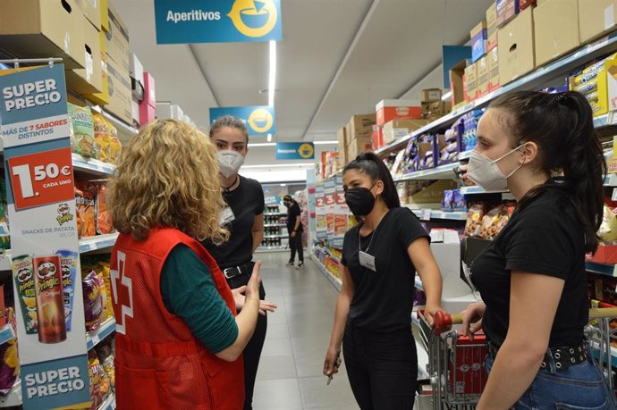 Archivo - Una voluntaria de Cruz Roja junto a tres trabajadoras en un supermercado.