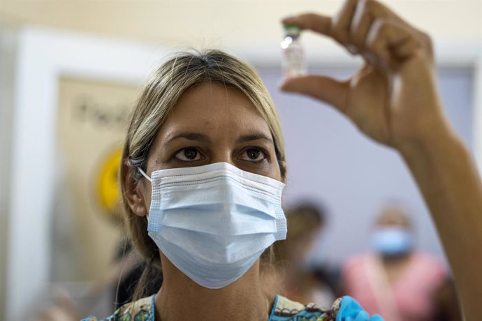 Archivo - Una mujer observa un vial de la vacuna contra el coronavirus Sputnik V.