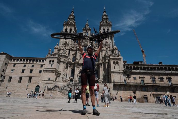 Un peregrino Portugués levanta su bicicleta al finalizar el Camino de Santiago, frente a la Catedral de Santiago, a 6 de junio de 2021, en Santiago de Compostela, A Coruña, Galicia, (España). 