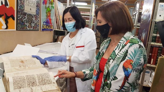 La vicealcaldesa del Ayuntamiento de Zaragoza, Sara Fernández, (dcha), observa el documento del Privilegio de los Veinte, del siglo XII, que se conserva en el Archivo Municipal, junto  con la archivera Elena Rivas.
