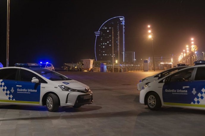 Dos coches de Policía aparcados en la playa de la Barceloneta, en una foto de archivo.