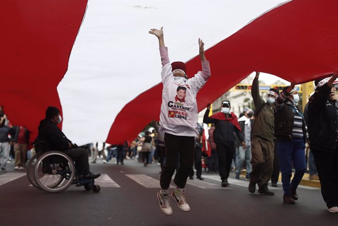 07 June 2021, Peru, Lima: A child jumps to touch a giant Peruvian flag held aloft by supporters of the presidential candidate of the left-wing Free Peru party Pedro Castillo during a rally. Castillo had received 50.28 per cent of the votes with over 96 