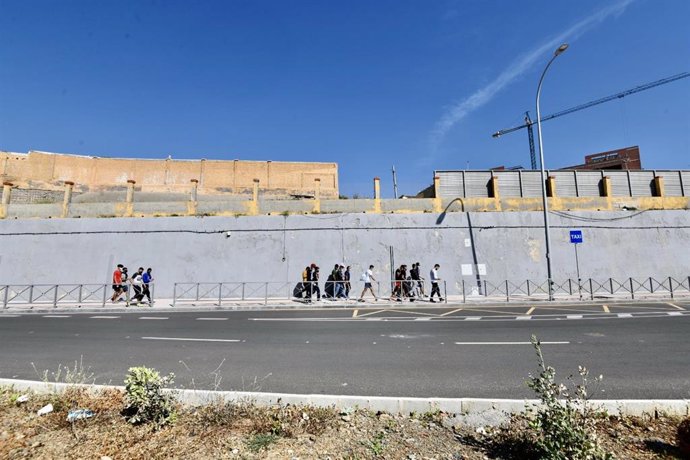 Varios migrantes procedentes de Marruecos hacen cola en las puertas de la frontera de Ceuta donde agentes de la Policía Nacional reparten citas para solicitud de asilo, a 2 de junio de 2021, en Ceuta (España). 