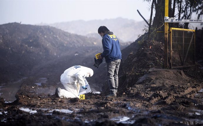 Archivo - Investigadores forenses recogen muestras entre las cenizas después de que varios camiones fueran incendiados en Chile.