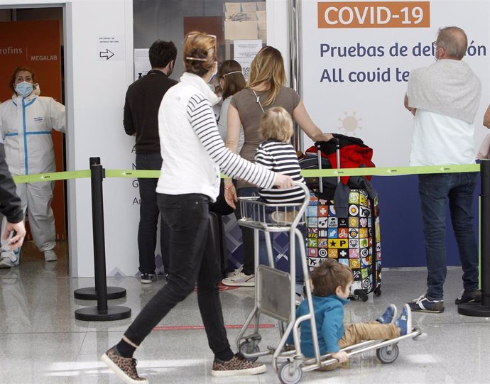 Archivo - Una pasajera se dirige al dispositivo de detección de Covid-19 colocado en el aeropuerto de Palma.