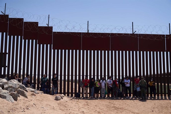 Archivo - Migrantes solicitantes de asilo se entregan a la Patrulla Fronteriza de Estados Unidos en el muro.