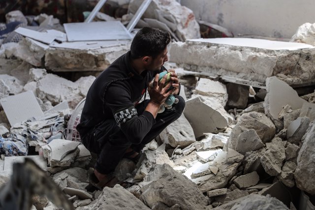 10 June 2021, Syria, Ibelin: A man holds a child's toy as he inspects the damages in a house after an airstrike by the Syrian regime targeted the town of Ibelin in Idlib Governorate. More than 10 people were killed. Photo: Anas Alkharboutli/dpa