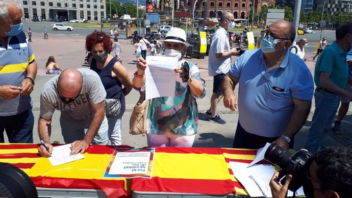 Algunas personas firman contra los indultos en la mesa instalada por el PP en la plaza Espanya de Barcelona.