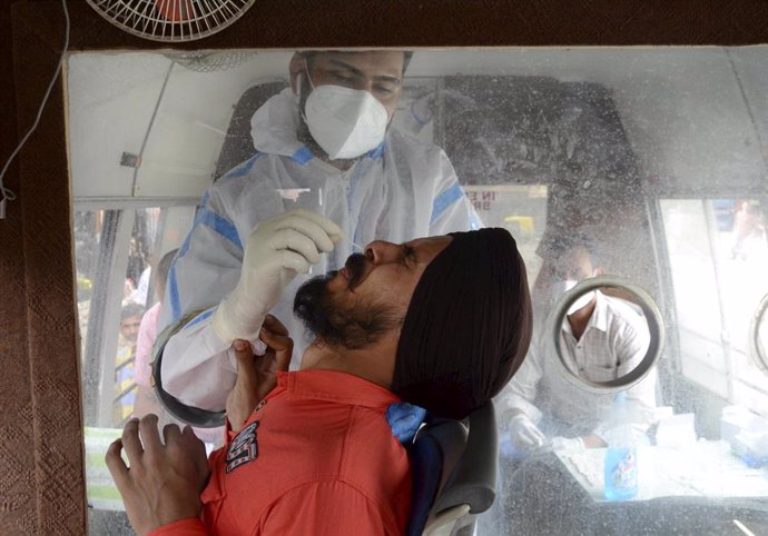 12 June 2021, India, Amritsar: A health worker takes a nasal swab sample from a person for Coronavirus (Covid-19) tests inside a mobile van. Photo: Shiva Sharma/PTI/dpa