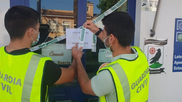 Agentes de la Guardia Civil precintan un establecimiento de Lotería en El Cuervo