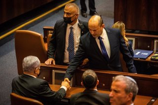 El primer ministro israelí, Naftali Bennett, da la mano al primer ministro saliente, Benjamin Netanyahu, en la Knesset