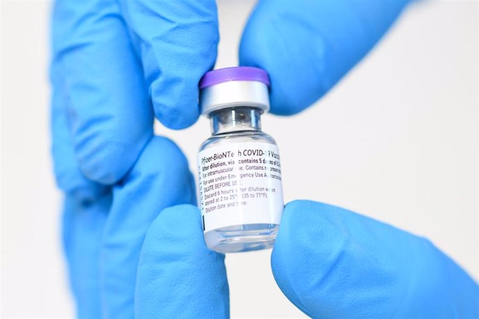 Archivo - FILED - 27 December 2020, Bavaria, Germering: A Bavarian Red Cross worker holds a vial of BioNTech/Pfizer vaccine at a vaccination centre. Pfizer and BioNTech are planning to donate 500 million doses of their joint coronavirus vaccine to the U