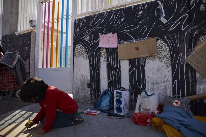 Archivo - Un niño dibuja a las puertas de un colegio.