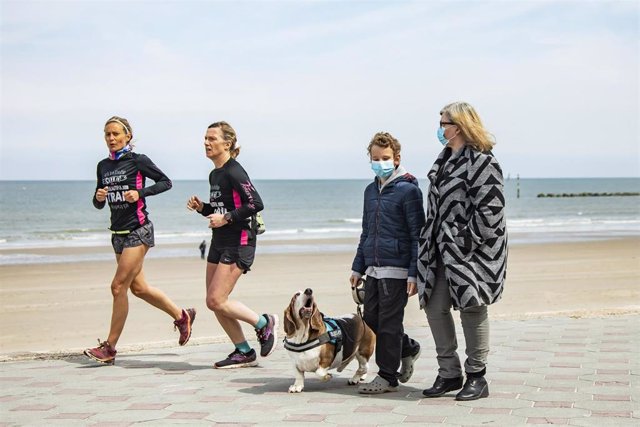 Archivo - Dos mujeres corren por la playa mientras que una mujer y un niño pasean un perro en una imagen de archivo de las playas de Dunkerque.