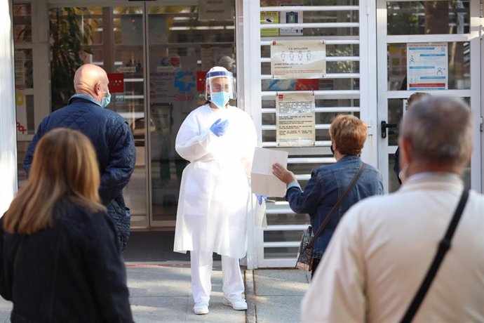 Archivo - Una sanitaria sale a atender a las numerosas personas que hacen cola en el Centro de Salud Vicálvaro-Artilleros en el distrito de Vicálvaro.