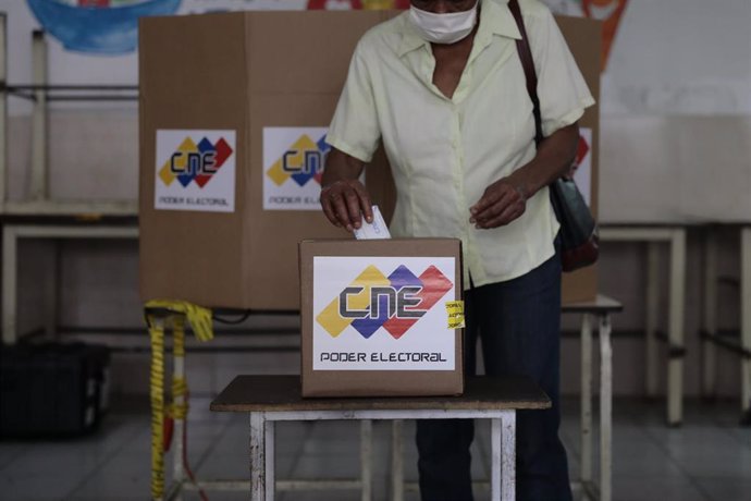 Archivo - Una mujer deposita su voto en una urna dentro de un colegio electoral durante las elecciones parlamentarias venezolanas de 2020.